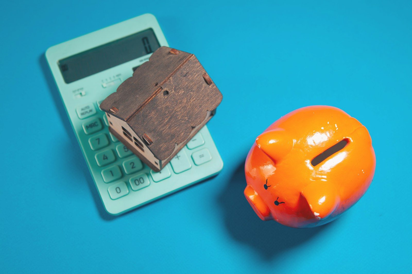 Photo by Sasun Bughdaryan Calculator, piggy bank, and house model on blue background